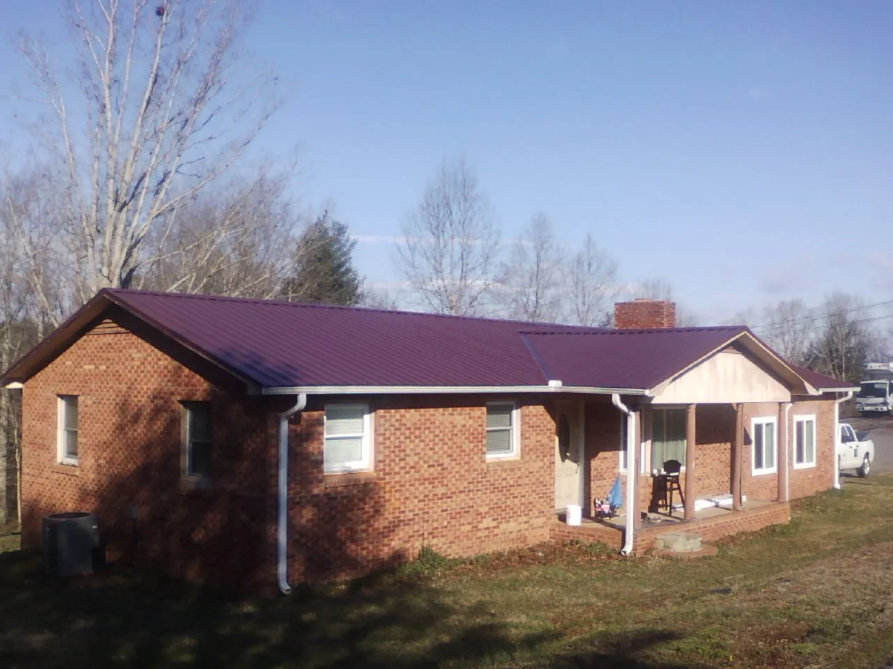 Burgundy metal roof on a brick ranch home with a new addition in Bolton